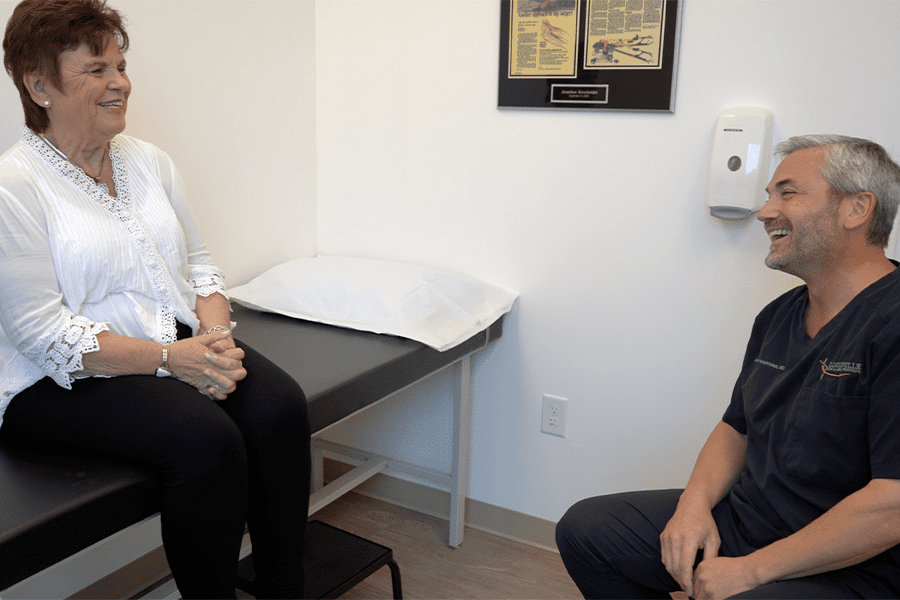 In an examination room, patient Sharon discusses her hip replacement surgery with Dr. Yerasimides of Lousiville Hip and Knee Institute