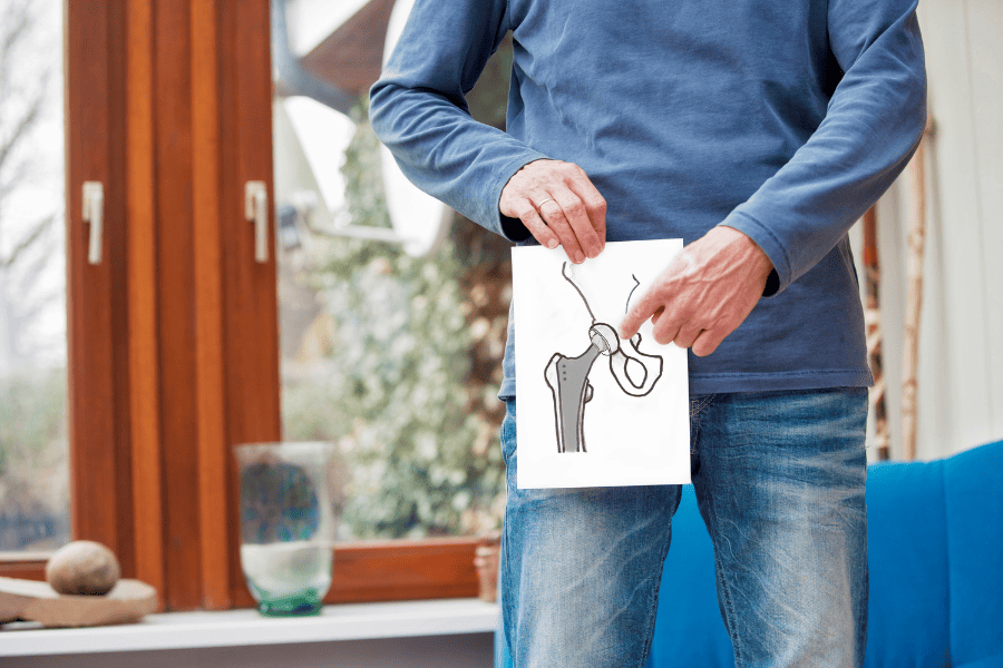 man holding illustration of hip replacement over hip